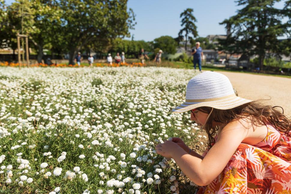 Jeune fille accroupie devant les plantes médicinales au jardin Camifolia