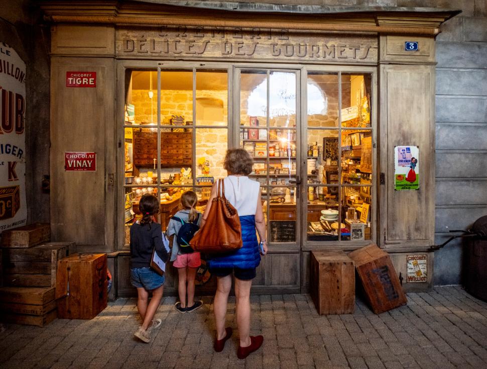 Maman avec ses enfants devant une boutique aux anciens commerces