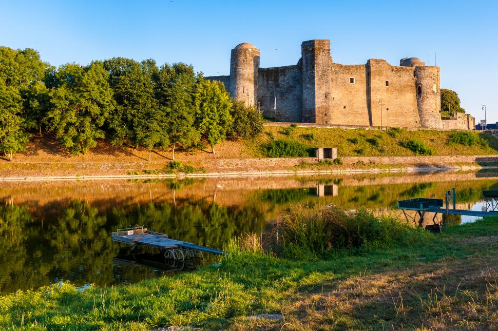 Vue sur le château de Pouancé, soleil couchant avec l'étang au premier plan.