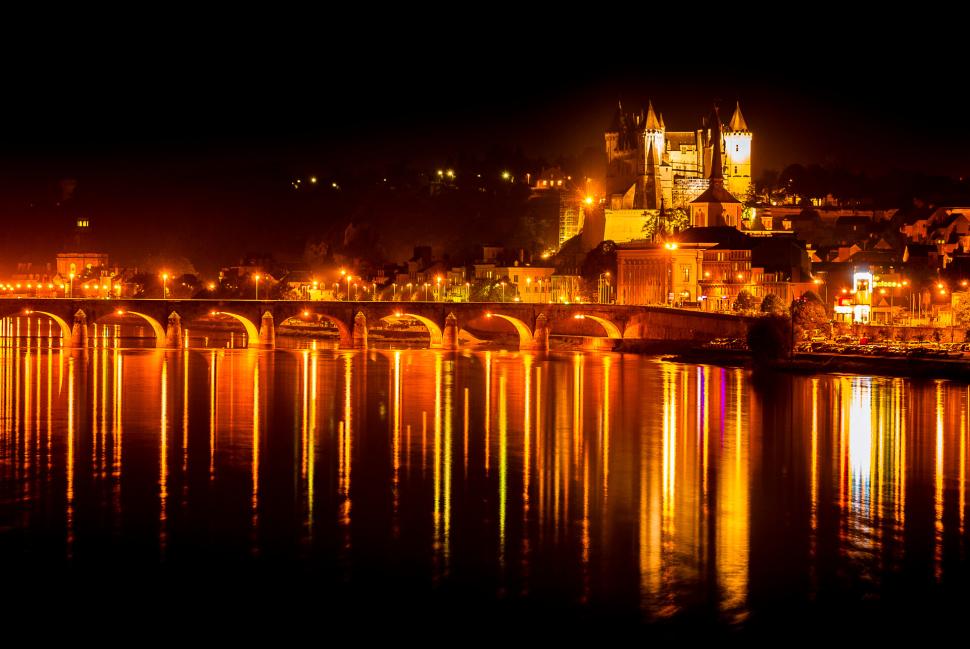 Saumur de nuit avec les reflets de la ville, le pont et le château, sur la Loire calme.