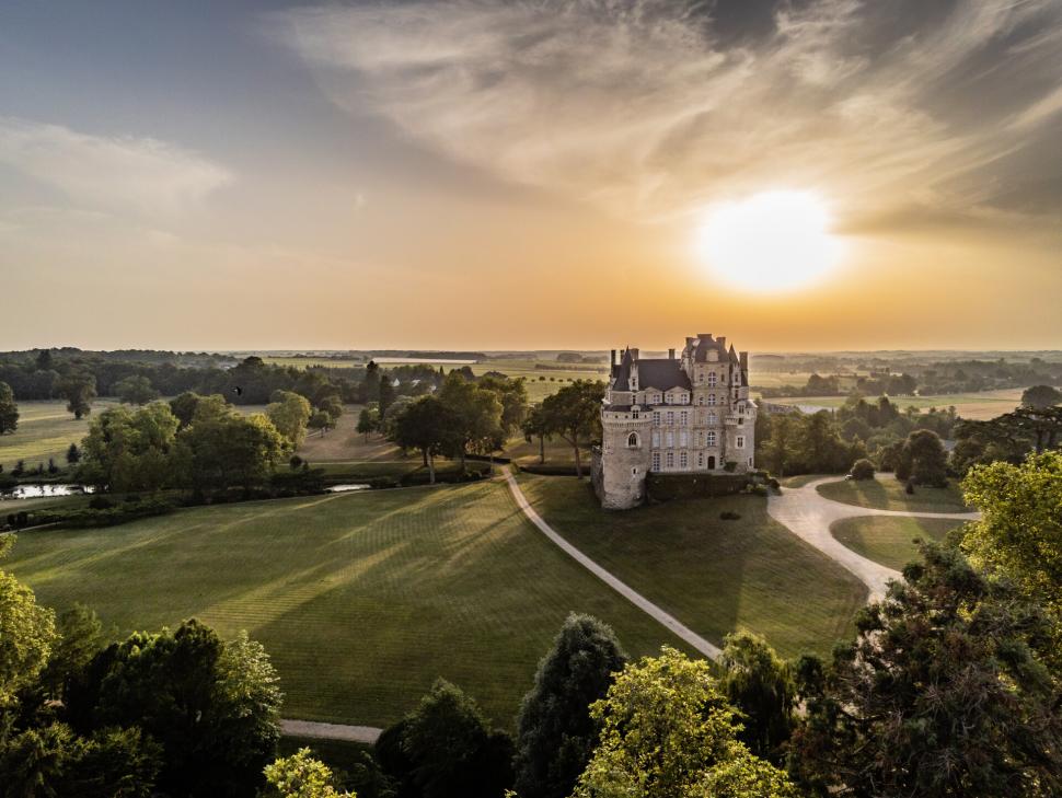 Vue aérienne du Château de Brissac et son parc paysager, sur un coucher de soleil