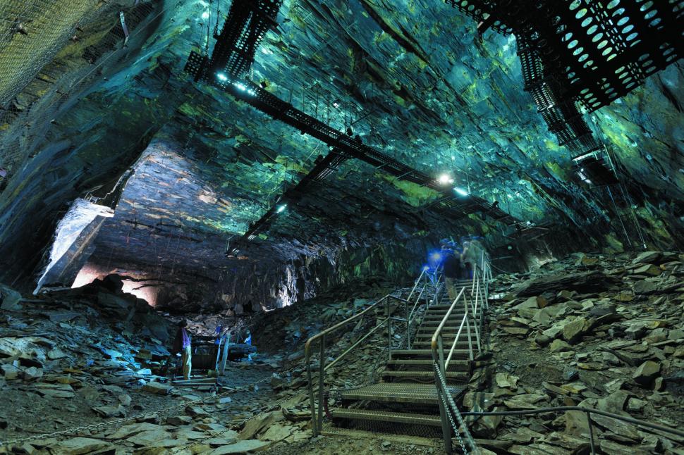Vue d'une grande chambre d'extraction d'ardoise, de hauts plafonds bleus et un escalier avec des visiteurs au centre de l'image