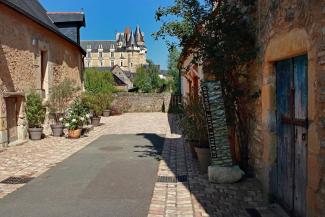 Ruelle pavée du quartier Saint Léonard, château visible en arrière plan sous un ciel bleu