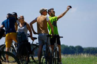 Groupe de 5 cyclistes pieds à terre, se prenant en groupe en selfie