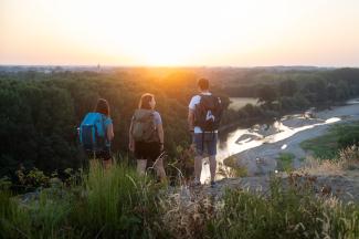 3 randonneurs à pied qui admirent le panorama à la Roche de Mûrs