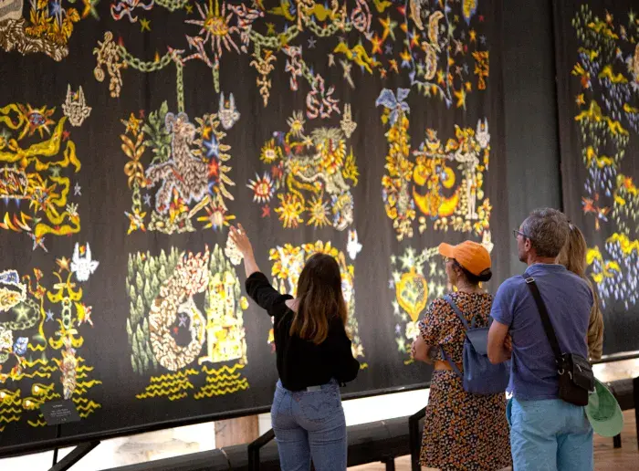 Personnes qui observent une tapisserie au musée Jean Lurçat
