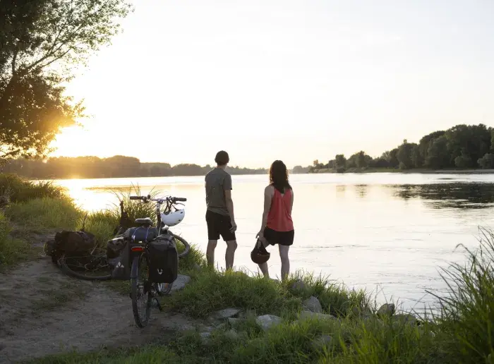 Couple à vélo qui admire le lever du soleil sur la Loire